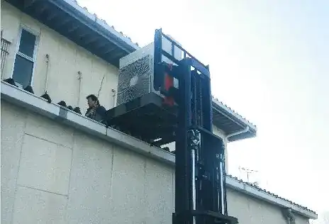 重機を用いた大型エアコンの据付作業