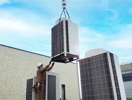 クレーンで設備用エアコン室外機を屋上へ搬入する作業